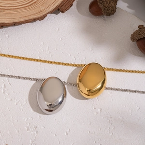 Détail de colliers avec pendentif ovale en finitions or et argent sur fond naturel épuré