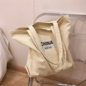 Détail du grand sac cabas en toile kaki avec imprimé CHINA noir sur une chaise