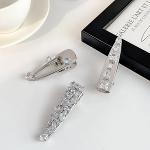 Close-up of three silver hair clips with micro-set zircon stones on white background