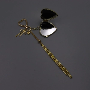 Detail of a golden heart flip mirror keychain with a bow pendant and lobster clasp