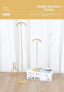 Set of two gold metal jewelry stands for necklaces on a wooden table with soft lighting