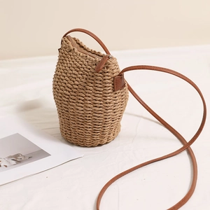 Brown hand-woven straw bucket bag with leather strap for summer beach vacations