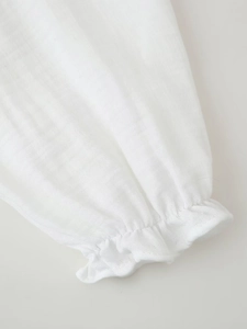 Détail d'une manche de chemise en coton blanc avec poignets élastiques et bordures volantées