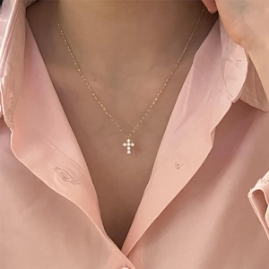 Close-up of golden 925 sterling silver cross necklace with sparkling white zircons on model