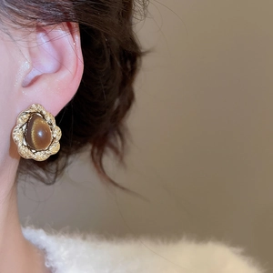 Close-up of vintage gold twist earrings with oval brown tiger eye stone on model ear