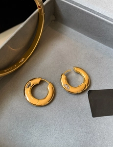 Detailed macro view of gold plated huggie earrings with marquise cut zircon stones