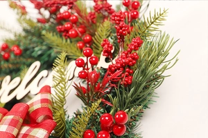 Macro shot of artificial red berries and pine needles with wooden Welcome sign