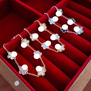 Close-up of three gold and silver four-leaf clover bracelets with mother-of-pearl insets