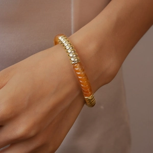 Détail d'un bracelet spirale en or et résine ambrée au poignet avec un style de luxe