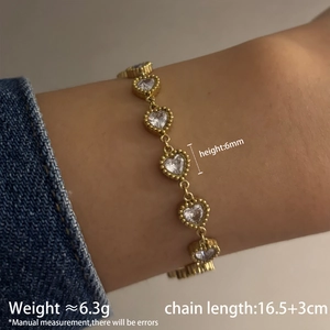 Gros plan d'un bracelet doré à maillons de cœur et zircons porté au poignet avec dimensions