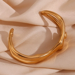 Close-up of gold plated stainless steel bangle with liquid metal wave texture
