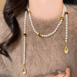 Detailed view of long pearl necklace with tiger eye beads and golden drop pendants