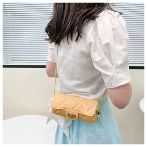 Beige quilted cylinder bag with pearl strap and gold lock shown in a lifestyle setting