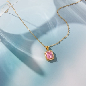Macro view of gold-plated necklace with a rectangular pink zircon and white diamond halo