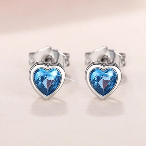 Macro shot of silver heart earrings with sparkling blue sapphire cut stones