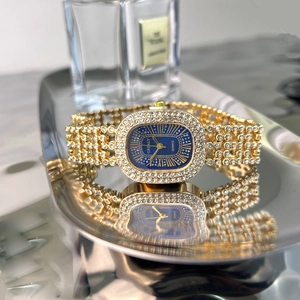Close-up of gold rhinestone watch with oval blue dial on reflective silver tray