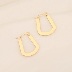 Close-up of gold geometric irregular U-shaped metal earrings with smooth polished finish