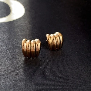 Primo piano di orecchini a sfera dorati con trama increspata vintage su sfondo in tessuto grigio