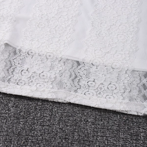 Détail d'une robe en dentelle blanche avec broderie ajourée et bordure festonnée