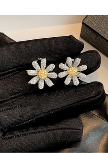 Detail of silver daisy stud earrings featuring yellow centers and sparkling cubic zirconia