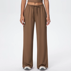 Detail of dark brown wide-leg trousers with elastic drawstring waistband and fluid drape