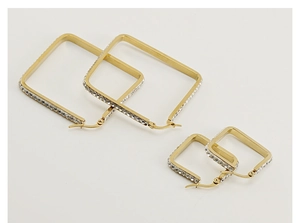 Flat lay of small and large square gold earrings with crystal inlay on white background