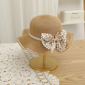 Détail d'un chapeau de paille pour filles avec dentelle et un grand nœud fleuri