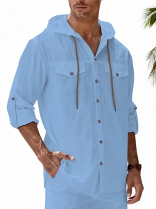 Detail of light blue linen hooded shirt featuring double chest pockets and buttoned cuffs