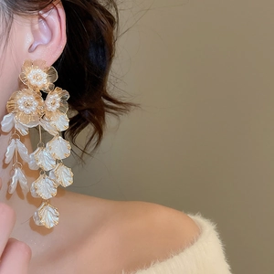 Detail of vintage flower tassel earrings with pearls on model, golden floral design