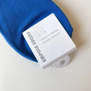 Close-up of blue cotton crew sock with authentic white brand tag on white background