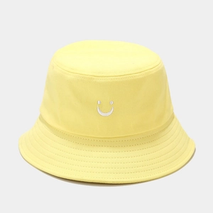 Détail d'un bob en coton jaune avec broderie smiley blanche et coutures sur le bord
