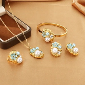 Detailed set of gold jewelry with pearls and blue flowers on golden silk fabric