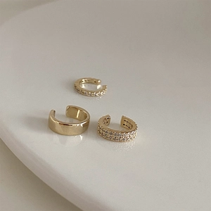 Three minimalist gold ear cuffs featuring polished metal and sparkling zircon stones