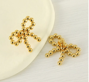 Close-up of golden bow-shaped stud earrings featuring a textured 18k gold plated bead design