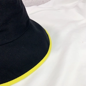 Vue détaillée du chapeau bob en sergé noir avec bordure contrastée jaune vif et coutures