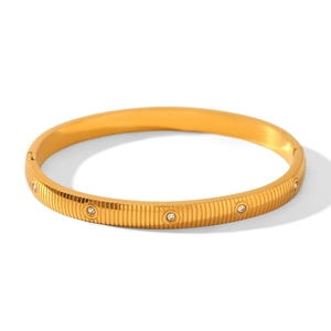 Detail view of gold stainless steel bangle featuring vertical grooves and clear zircon stones