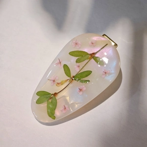Handmade resin hair clip with real pink flowers and green leaves on white background