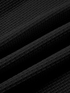 Macro shot of breathable black waffle knit fabric showing honeycomb texture on men's t-shirt