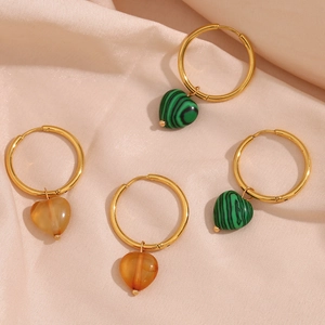 Detailed shot of gold heart hoop earrings with malachite and amber stones on pink silk