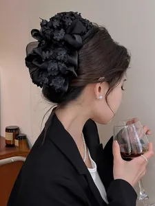 Détail d'une grande pince à cheveux fleurie noire multicouche sur une coiffure élégante