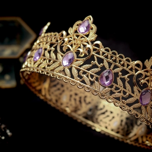 Macro detail of luxury golden baroque crown with purple rhinestones and intricate carvings