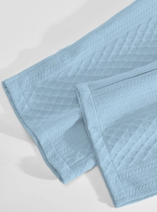 Close-up of light blue waffle knit fabric showing premium texture and quality stitching