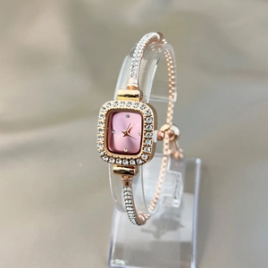 Close-up of rose gold square watch with pink dial and rhinestone bracelet details