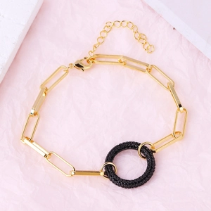 Detail of a gold plated link bracelet featuring a black crystal inset pendant and lobster clasp