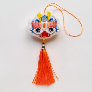 Détail d'un pendentif lion de danse chinoise en peluche blanc et orange avec broderie