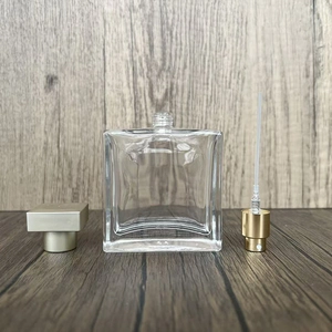 Detail view of square glass perfume bottle with gold spray pump and cap on wood