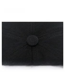 Detail of a black cotton baseball cap showing top button and six-panel stitching design