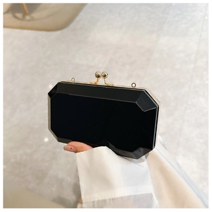 Macro view of a black acrylic octagon evening bag with a gold metal frame and bead clasp