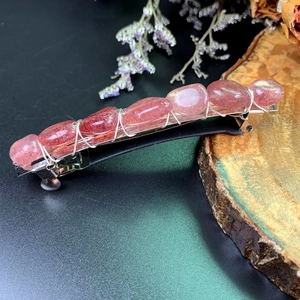 Bohemian crystal hair clip with pink stones and silver wire on a natural wood base