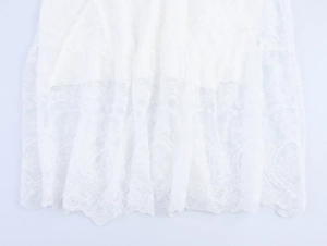 Λεπτομερής κοντινή λήψη λευκού δαντελωτού υφάσματος με κέντημα και κυματιστό στρίφωμα
